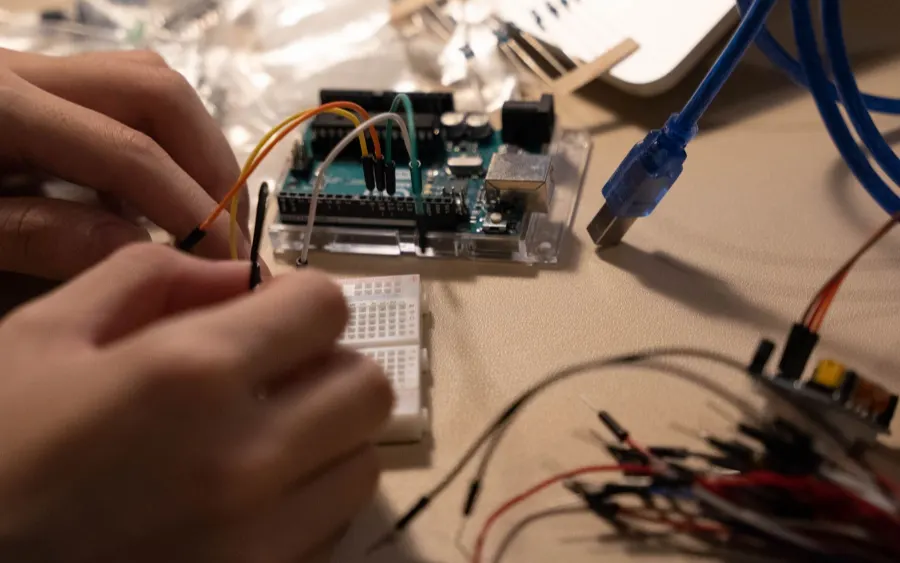 Bir el, breadboard üzerindeki mikrodenetleyiciye jumper kablo bağlıyor